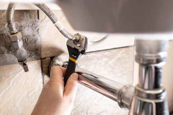 hand-fixes-flexible-hoses-sink-by-wrench hand-fixes-flexible-hoses-sink-by-wrench